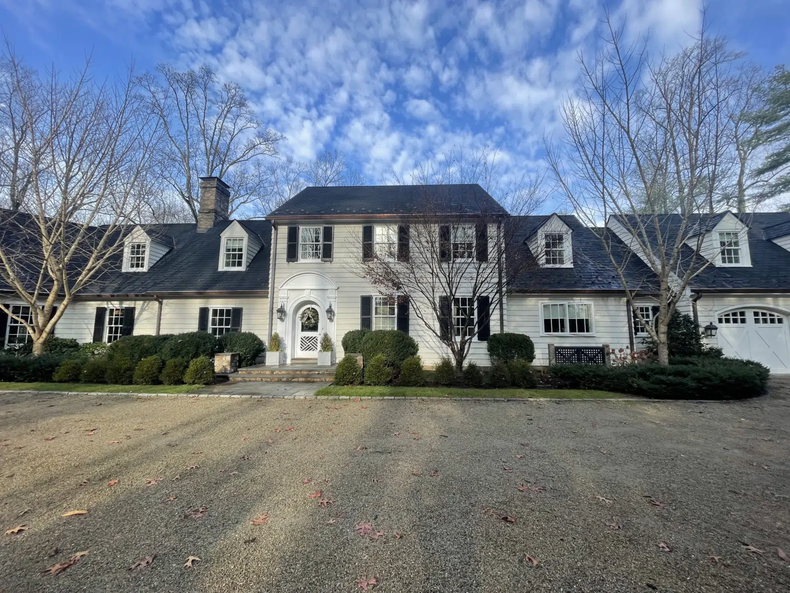 White colonial house with black shutters under blue sky — Alvarez' Painting in Charlottesville